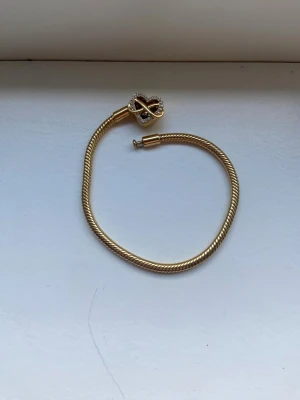 Pandora Moments Sparkling Infinity Heart - Snyggt guldarmband med tvinnad kedja och ett hjärtformat lås dekorerat med glittriga stenar och infinity-symbol. På baksidan av låset står det 'Family forever and always'. Perfekt för dig som gillar personliga detaljer och elegant stil.
