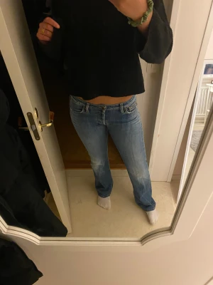 Blå bootcut jeans från Replay - Säljer ett par blåa Replay jeans med låg midja och bootcut passform. Jeansen har och knappar framtill istället för dragkedja. Materialet är slitstarkt denim och färgen är ljusblå med snygga slitningar på låren. 