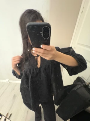 Svart blus från Gina Tricot - Svart blus från Gina Tricot med v-ringning och knytband framtill. Men lappen där storleken visas är av på ena sidan.Blusen har voluminösa, långa ärmar med resår vid ärmslut och rynkade detaljer över bröst och rygg. Säljer denna för jag inte använder den💗pris kan snackas