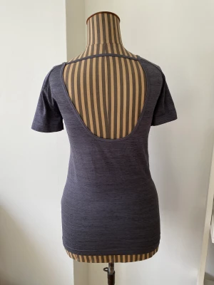 Sporttopp från Under Armour - Snygg sporttopp från Under Armour. Lite djup i ryggen och mindre urringad framtill. Fin grå färg och superlätt. Använd ett par gånger och i nyskick.