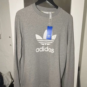 Ny adidas tröja - Helt ny och oanvänd tröja från Adidas, grå, storlek S men passar även M. Nypris ca 700kr