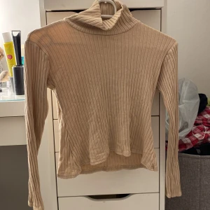 Ribbad tröja - Ribbad beige tröja i Stretchigt material från NLY TREND. Superfin, jätteskön med hög hals. Använd några gånger. Säljer för 35kr+frakt