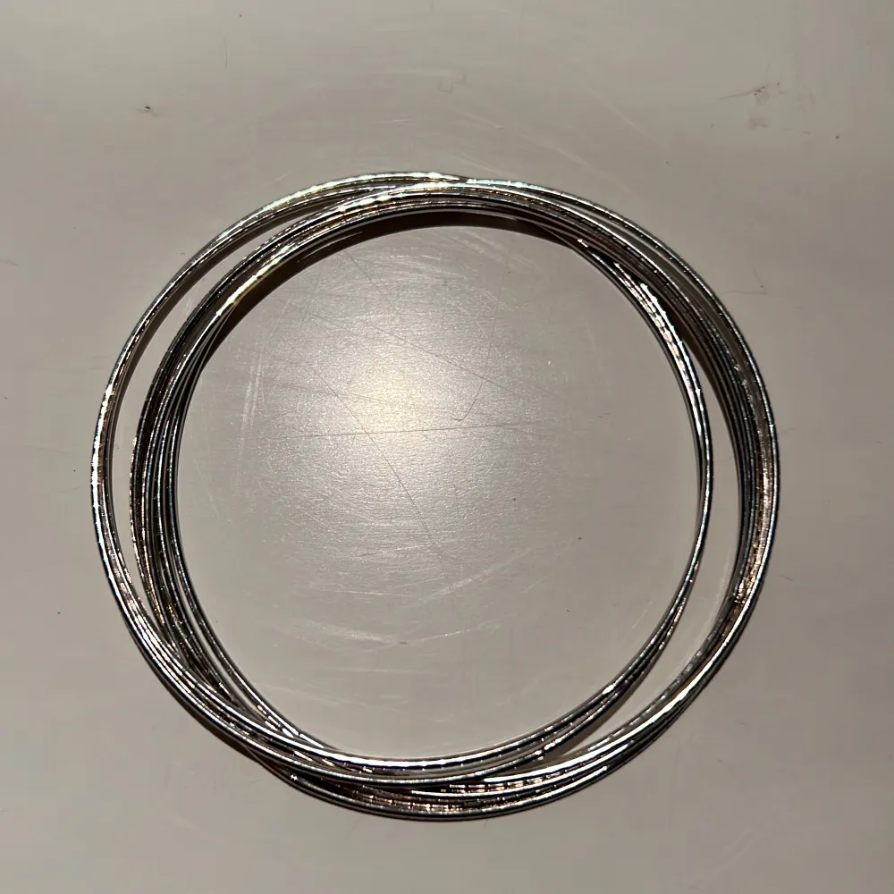 Armband i silvermetall. 7 tunna ringar som sitter ihop.  Ca 6 cm i diameter. Finns på Hägerstensåsen i Hägersten. . Accessoarer.