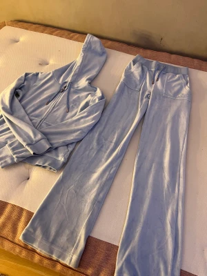 Ljus blått juicy set - Jag säljer detta juicy set för att det är för litet för mig, det är storlek xxs på byxorna och xs på koftan, metall grejerna på snöret är lite rostigt pågrund av att jag tvättat dom mycket, men man tänker ej mycket på det. Orginalpris:2400 kr