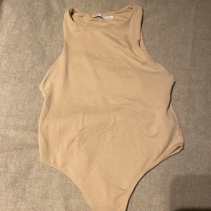 Beige body - Beige stringbody från Zara i polyamid (stretchig) och sitter tajt mot kroppen/seamless. Inte nopprig och använt 1 gång då den är för liten. Den är väldigt bekväm o elegant. 
