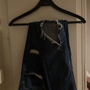 Jeans m hål  - Ett par mörkblåa jeans från Gina med hål i. Modellen är Kristen. De är i nyskick. Säljer pga för små för mig.