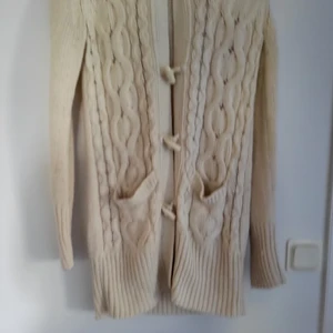 Lång stickad kofta med luva - Lång stickad kofta med luva. Plagget har noppror. 