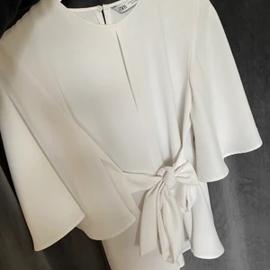 Vit blus  - Vit blus med en knytning där fram eller bak, beroende på vad man själv föredrar. 