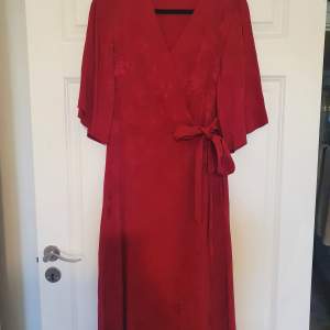 Röd klänning i omlott modell med knytning på sidan.  Köpt på Kappahl,  stl 36. Fint skick, knappt använd. 