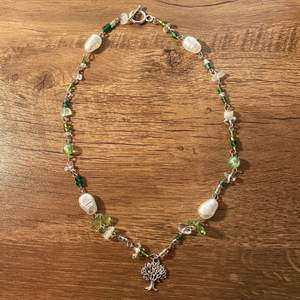 ett halsband som jag gjort själv! gjort av bland annat sötvattenpärlor, kristallchips, genomskinliga plastpärlor, andra pärlor i olika gröna nyanser och en berlock i silver💚