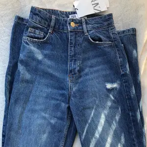Snygga mörkblå jeans från Zara! Storlek 32, raka i modellen, höga i midjan, går över skon och har slitningar vid knäna. Aldrig använda och med prislappen kvar. Säljer för 200kr! 🌟