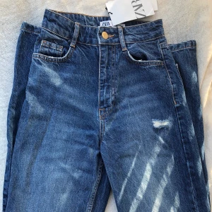 Mörkblå ZARA jeans - Snygga mörkblå jeans från Zara! Storlek 32, raka i modellen, höga i midjan, går över skon och har slitningar vid knäna. Aldrig använda och med prislappen kvar. Säljer för 200kr! 🌟