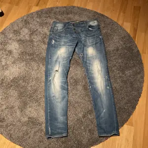 Detta är ett par blåa jeans i storlek medium.Det finns ett hjärta i silver på baksidan på höger ficka.Hålen är menade/det ska vara så. Byxorna är i  fint skick. 