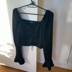 FEST BLUS-BIKBOK - Fin festlig blus från BIKBOk, har volanger på armarna och en knytning fram. Bara använd 1 gång. 