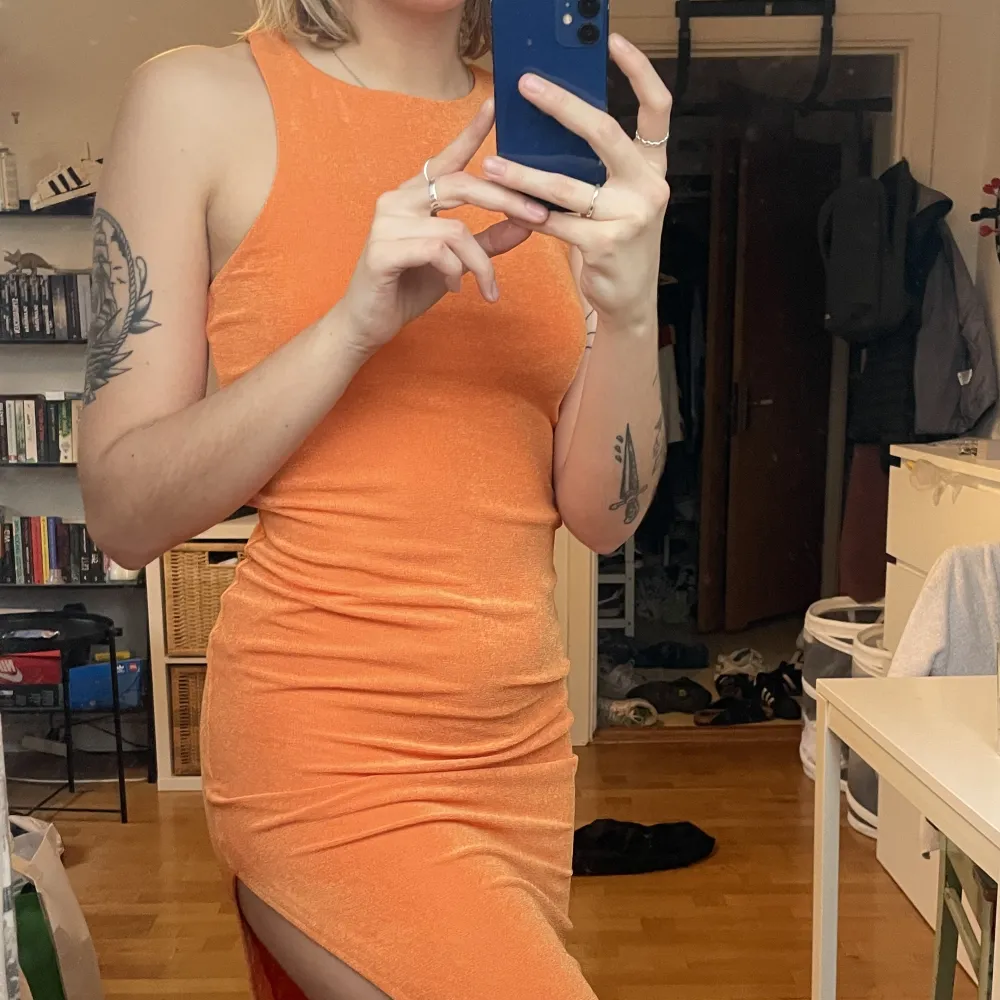 Super fin klänning i skimrande orange! Har en slits på vänster sida. Den har även en underkjol så den inte blir genomskinlig!. Klänningar.