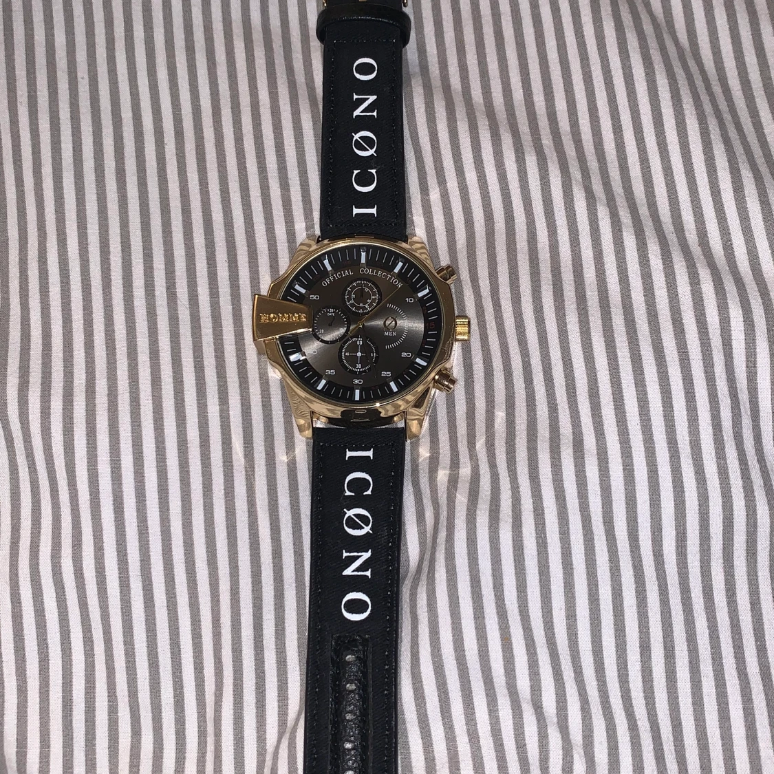 En klocka med svart tyg armband.