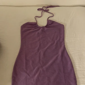 Lilaglittrig klänning!  - En snygg figurnära klänning som är lilaglittrig. Säljs då den inte används längre, endast använd fåtal gånger. Lite sliten på snöret upptill, därav priset.   Kan mötas upp i Stockholm! 