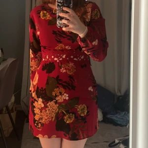 Röd blommig klänning - Klänning från AX Paris. Använd ett fåtal gånger och är i bra skick! Köparen står för frakten:)