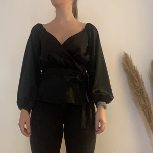 Blus - Svart, pösig blus som går ha på två olika sätt. Band i midjan som skapar fin volang nedtill. 1. Där man viker in ärmarna i banden vid axlarna 2. Låter ärmarna hänga ner  Använd några gånger bara.