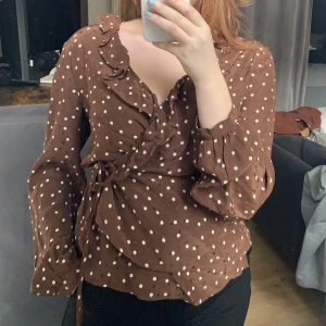 Brun prickig omlott blus HM 42 - Brun prickig omlott blus från HM storlek 42, men jag är en S och kan dra åt den så sitter den bra! 