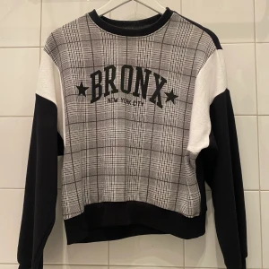 Grå Bronx Sweater / Sweatshirt  - Snygg sweater i grått, svart och vitt med BRONX logga på. Storlek S. Från rökfritt och djurfritt hem. Kan mötas i Centrala Stockholm eller frakta. Skriv vid frågor eller intresse! 