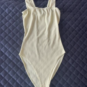 Ribbad body - Ribbad body i ljusgul färg. Motsvarar storlek XS.