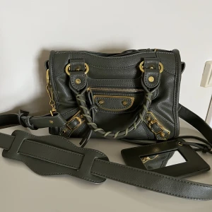 Väska - Säljer denna superfina mörkgröna väskan med guldiga detaljer🌸. Rymmer mycket och är i väldigt bra storlek, väldigt bra skick! Man får med långa  bandet och spegeln. Köpt för 1000kr här på Plick men säljer för 700 kr exklusive frakt. 