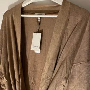 Oanvänd kofta från B.young prislapp kvar - Helt nya koftor från B.young  Tunn beige knälång kofta med 2 fickor fram och knyte i midjan  7 st i olika storlekar   2st XXL 2st XL 2st L 1st M 1st S Helt nya med prislapp kvar Nypris 499kr 