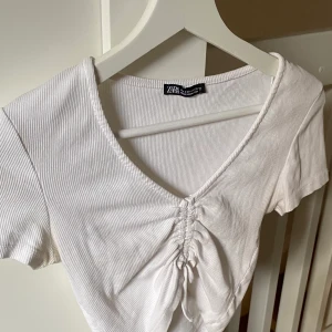 T-shirt med dragdetalj - Vit t-shirt med justerbar dragdetalj som bestämmer hur kort och tight du vill att den är! Köparen står för frakten, pris går att diskutera🤍