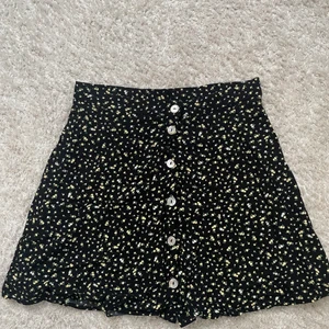 Kort rak kjol - En svart rak kjol i mjukt tunt tyg med små gulvita blommor på. Säljer pga inte min stil. Använd fåtal gånger förra sommaren men ser ut att vara i nyskick. Köparen står för frakt, den kan även välja frakttyp. Pris kan diskuteras. Skriv för mer info eller bilder. 