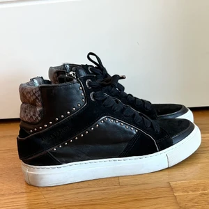 Sneakers från Zadig&Voltaire - Säljer dessa trendiga skor då de är för små tyvärr! Därmed är de använda bara 2 gånger! Alltså nästan perfekt skick. Dessutom så himla snygga med orm mönstret där bak på skorna. Skorna har även en dragkjedja på innersidorna så man slipper knyta varje gång.Hoppas någon får bra användning för skorna🖤 