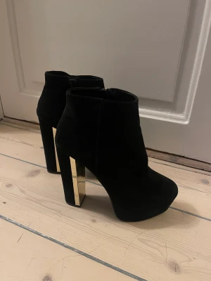 Aldo platåskor  - Klackskor från Aldo i svart mocka med platå. Detalj guldkant på klack. Storlek 37,5