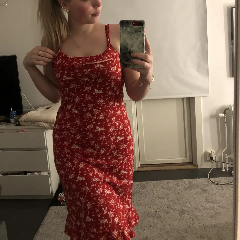Säljer denna röda kläning med vitt blommönster då jag aldrig använder den då jag inte tycker jag själv passar i färgen röd och den är lite för stor. Lite volanger vid brösten och nertill. Klänningar.