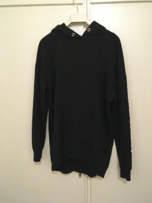 Hoodie - Svart hoodie med text på en arm. Lite nopprig