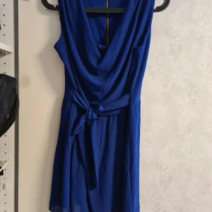 Söt blå klänning - Väldigt söt blå klänning med knytning i midjan. Väldigt skön på sommaren. Använd 1 gång sen tyckte jag att den var för kort tyvärr.  Storleken är L men jag är storlek M och 176 lång