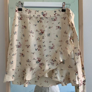 Beige blommig kort kjol - Kort beige kjol med blommor på. Volang. Superfin