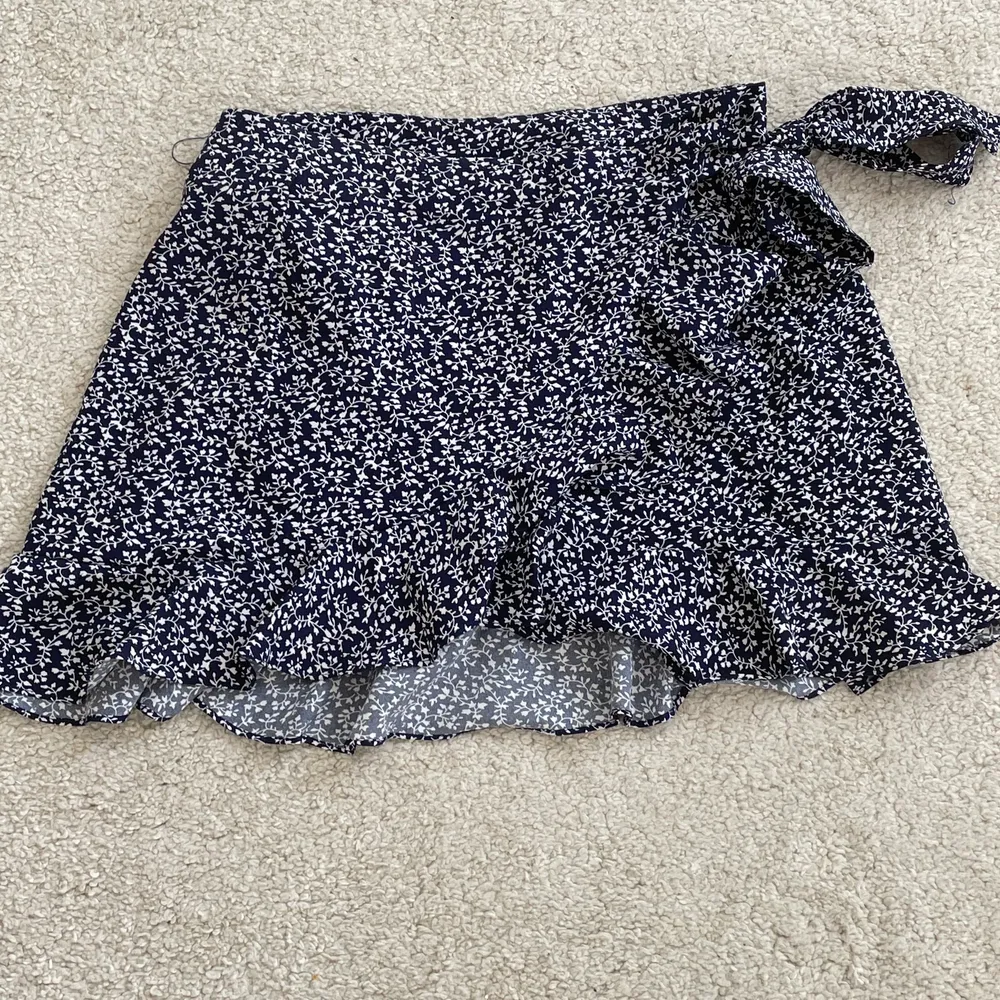 Säljet denna blommiga kjolen då den inte kommer till använning. Den är i den kortare modellen. Men den är sjusterbar då det är en omlottkjol med band som man knyter. Frakt tillkommer. Kjolar.