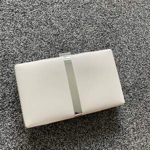 Kuvertväska från Tamaris i en beige färg med silver detaljer. Höjd: 12 cm Längd: 20 cm Vidd: 4 cm