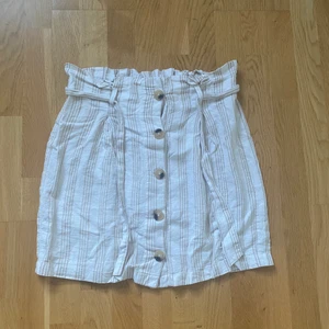 Kjol från Gina Tricot Strl 38 - Vit/beige randig kjol från Gina Tricot i Strl 38. Kjolen slutar en bit ovanför knäna på mig som är 168 cm 