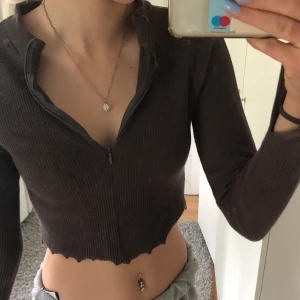 Ribbad långärmad topp - Ribbad långärmad topp med dragkedja och slits i armarna. Svårt att se färgen på bilderna men den är mörk lila grå typ. Strl M. Vet ej vart den kommer ifrån för den är köpt secondhand. 30kr +frakt