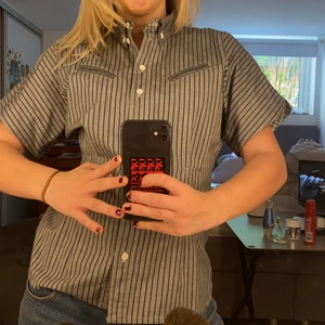 Söt skjorta - Söt randig grå skjorta! Lite insydd så sitter fint runt midjan! Kortärmad så skön nu mot sommaren! Sitter bra på mig som brukar ha S!💖💓💖💓