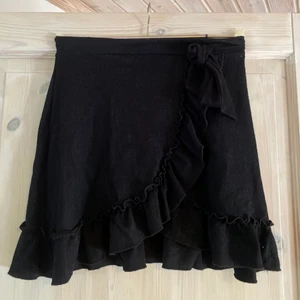 svart volangkjol - en svart vanlig volangkjol från gina med rosett man kan knyta vid midjan, storlek s