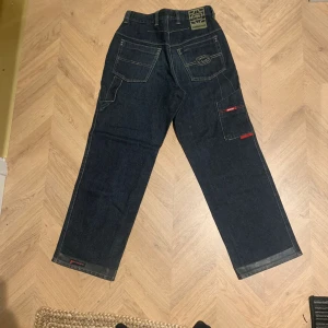 Baggy echō jeans jnco liknande  - Rare  baggy jeans med sjuka detaljer från echō unltd i näst intill nyskick. Kanterna vid botten är vaxade så de ska hålla längre och inte trampas sönder i "anti fraying system" skriv vid intresse,pris kan diskuteras😊Kan skicka bild på alla detaljer privat