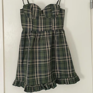 Grön rutig klänning  - Helt oanvänd, prislapp kvar! Bara provat den men var tyvärr alldeles för liten för mig och skulle säga att den snarare är i strl xs! Grön, rutig och ganska kort. Kan justera axelbanden. 