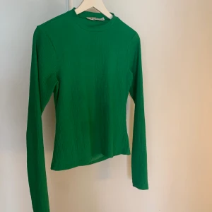 Grön topp Na-kd  - Snygg grön topp med öppen rygg från Na-Kd. Endast använd ett fåtal gånger och därför i väldigt bra skick. 