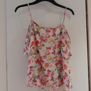 Blommig blus S - Sommarblus med öppen rygg och bara axlar. Använd fåtal gånger. Säljer pga för liten. Kontakta gärna om frågor<3