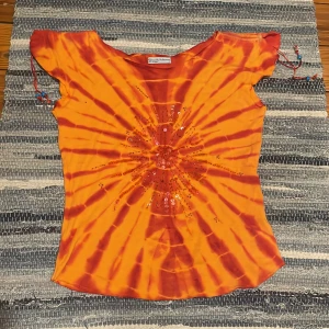 orange paljett topp - orange topp med tie dye mönster och paljetter. knytning på axlarna som går att dra ihop.