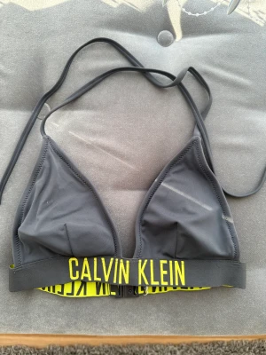 Bikini överdel+underdel - Säljer min bikini från ck färgen grå storlek XS. Fint skick inga fläckar eller hål!