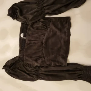 Svart silkestop - Svart top från Gina tricot med croppad rygg och ärmslut  . Svart glansigt tyg i stl 32