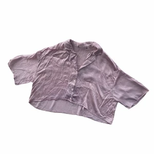 KORT BLUS ZARA - En midjekort blus från Zara i ett glansigt material. Färgen är en nyans av ljusare lila. 